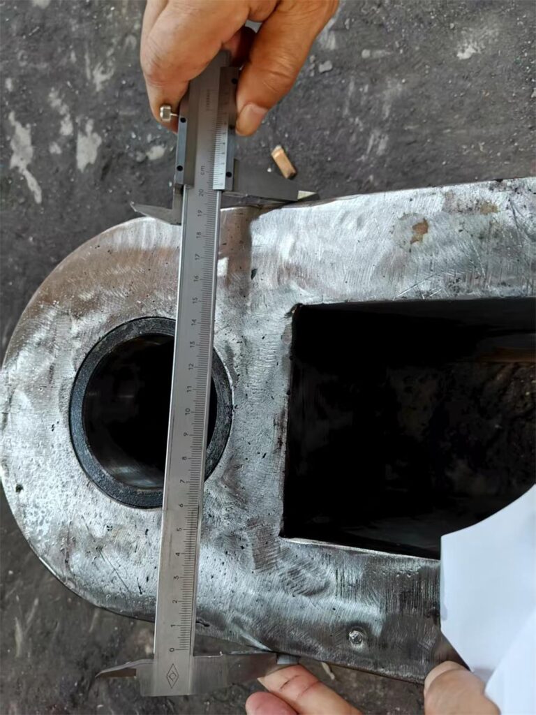 Close-up of custom welded part being inspected with micrometer